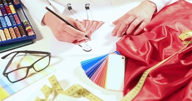 Artist drawing a dress and picking fabric colours