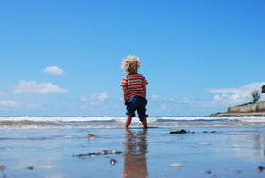 Small child standing in the water at a beach