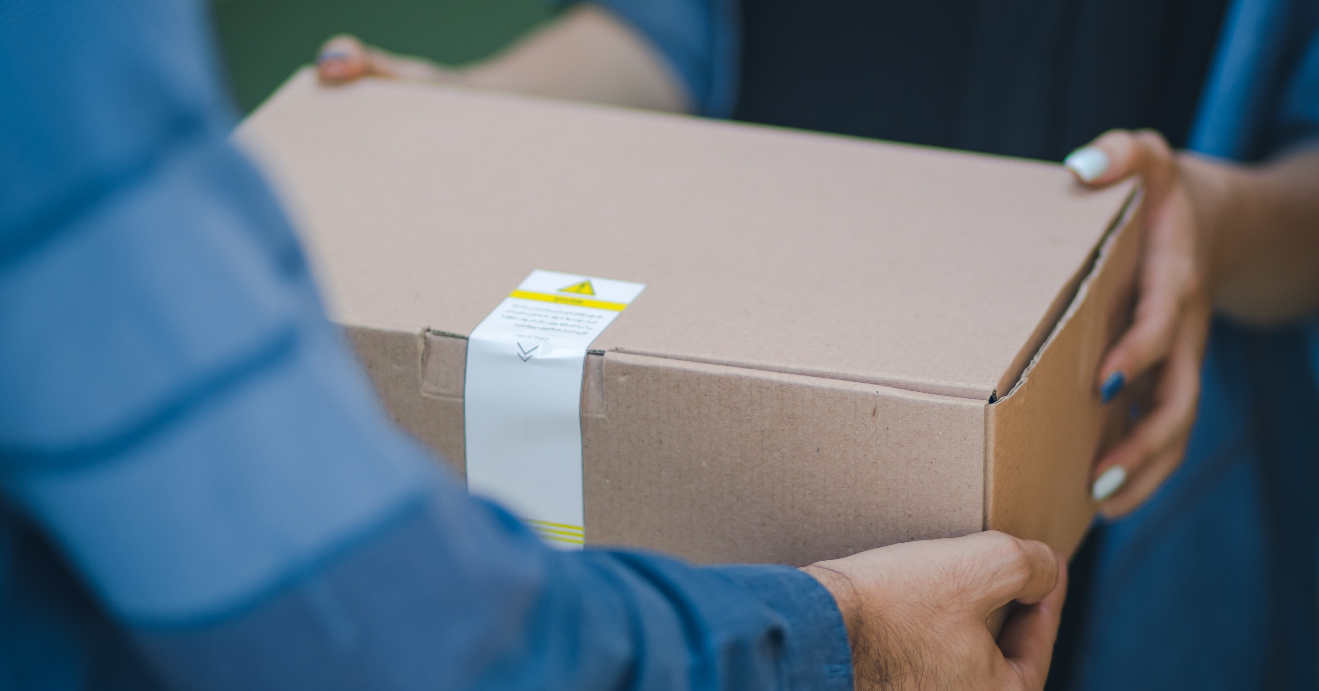 Woman passing a cardboard package to a man